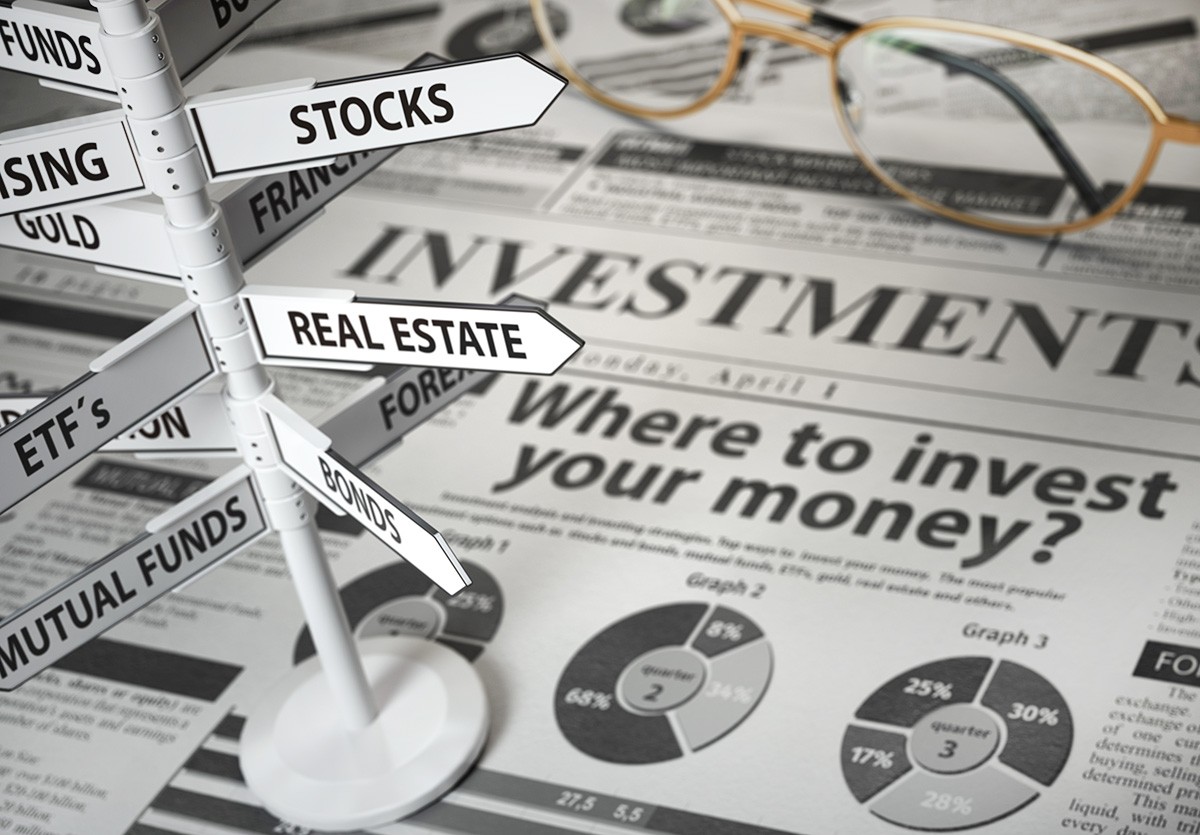 Investment options signpost showing stocks, real estate, bonds, mutual funds, and ETFs on a financial newspaper